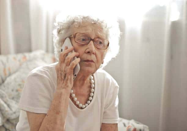 An elderly woman sitting on a call with a worried look on her face